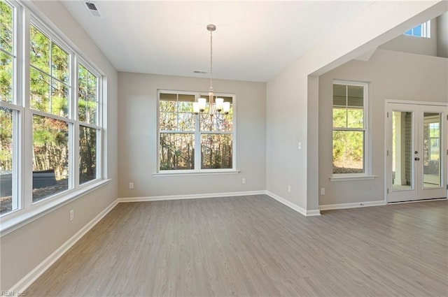 unfurnished dining area with a chandelier, visible vents, baseboards, and wood finished floors