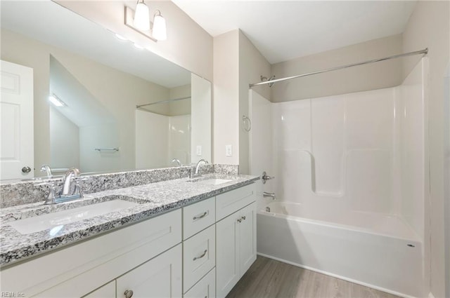 full bathroom featuring double vanity, wood finished floors, tub / shower combination, and a sink