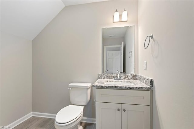 bathroom featuring toilet, baseboards, vaulted ceiling, and vanity