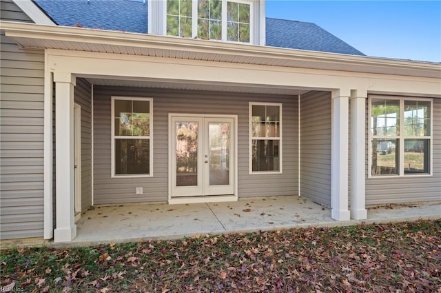 property entrance with a patio area and roof with shingles