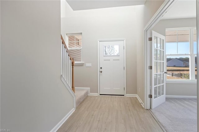 entrance foyer featuring stairs, light wood finished floors, and baseboards