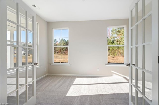 empty room with carpet, visible vents, baseboards, and french doors