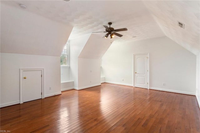 additional living space with ceiling fan, visible vents, baseboards, vaulted ceiling, and wood-type flooring