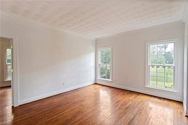 empty room with visible vents, baseboards, crown molding, and wood finished floors