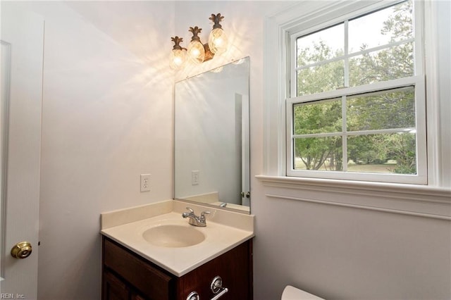 bathroom with toilet, a wealth of natural light, and vanity