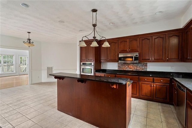 kitchen with visible vents, hanging light fixtures, appliances with stainless steel finishes, light tile patterned flooring, and a kitchen bar