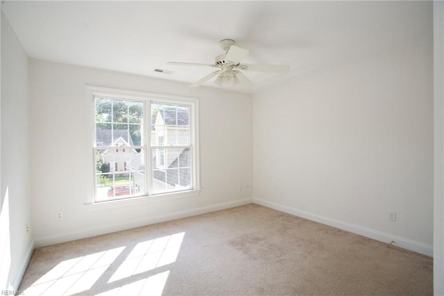 empty room with carpet floors, ceiling fan, visible vents, and baseboards