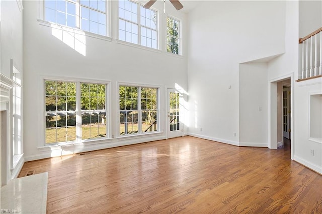 unfurnished living room with wood finished floors, a ceiling fan, and baseboards