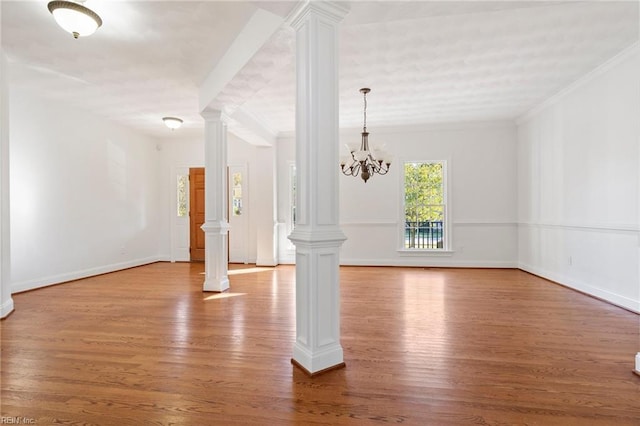 interior space with a chandelier, wood finished floors, baseboards, ornamental molding, and decorative columns