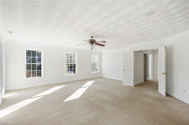 spare room with light colored carpet, crown molding, a textured ceiling, and baseboards