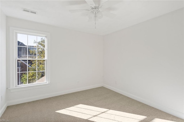 spare room featuring carpet, visible vents, ceiling fan, and baseboards