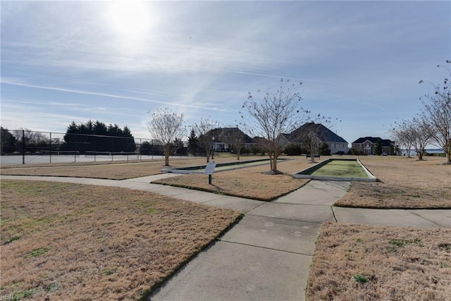 view of property's community featuring a yard and fence