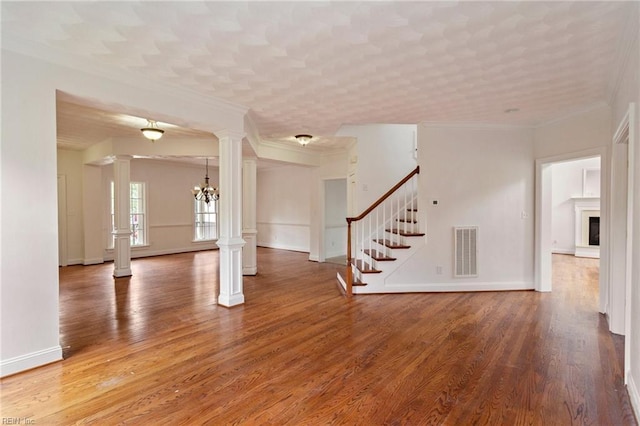 unfurnished room featuring decorative columns, stairs, visible vents, and wood finished floors