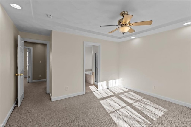 unfurnished bedroom featuring baseboards, light colored carpet, a raised ceiling, and recessed lighting