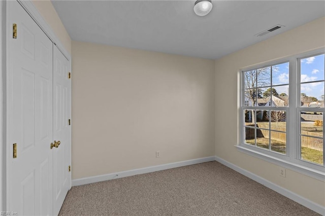 unfurnished bedroom featuring carpet floors, a closet, visible vents, and baseboards