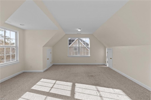 additional living space featuring vaulted ceiling, light carpet, and baseboards