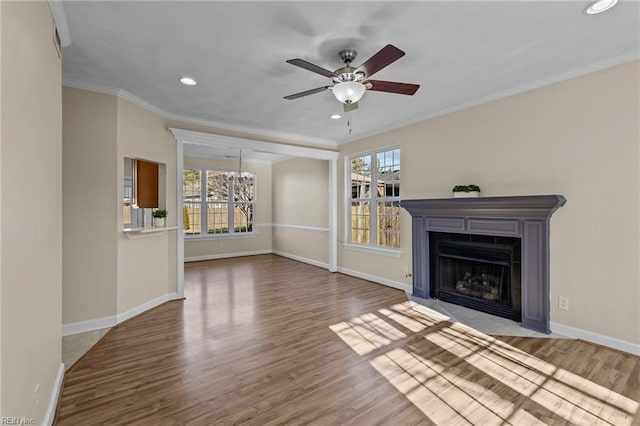 unfurnished living room featuring plenty of natural light, crown molding, and wood finished floors