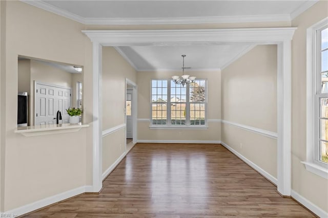 unfurnished dining area featuring baseboards, a chandelier, wood finished floors, and ornamental molding