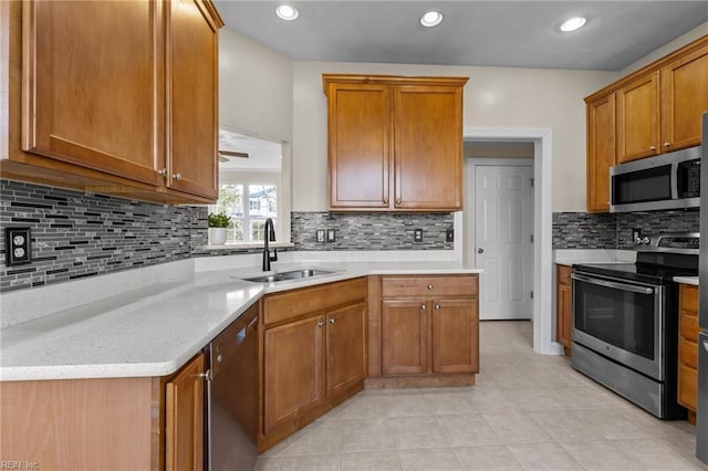 kitchen featuring brown cabinets, recessed lighting, appliances with stainless steel finishes, a sink, and light stone countertops