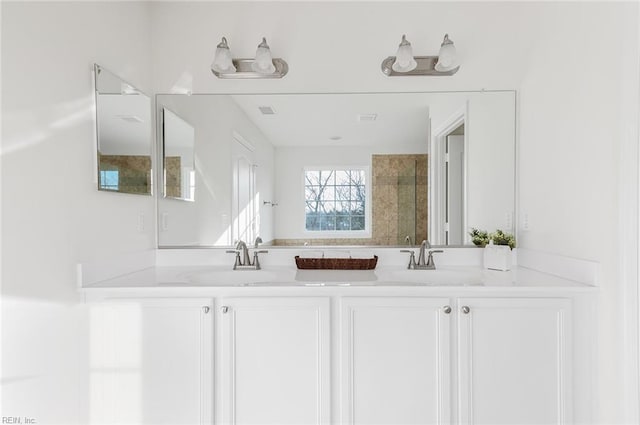 full bath with visible vents, a sink, a tile shower, and double vanity