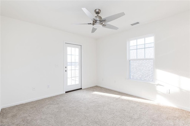 carpeted empty room with ceiling fan, visible vents, and baseboards