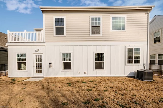 back of property with board and batten siding, fence, a lawn, and central air condition unit