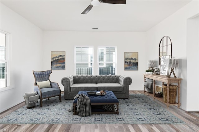 living area featuring a ceiling fan, visible vents, and wood finished floors