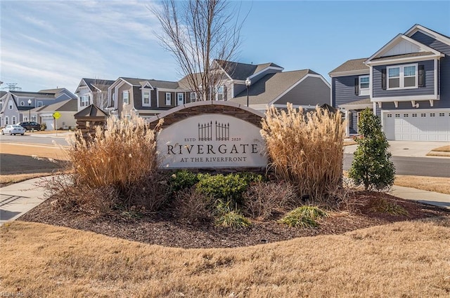 community sign featuring a residential view and concrete driveway