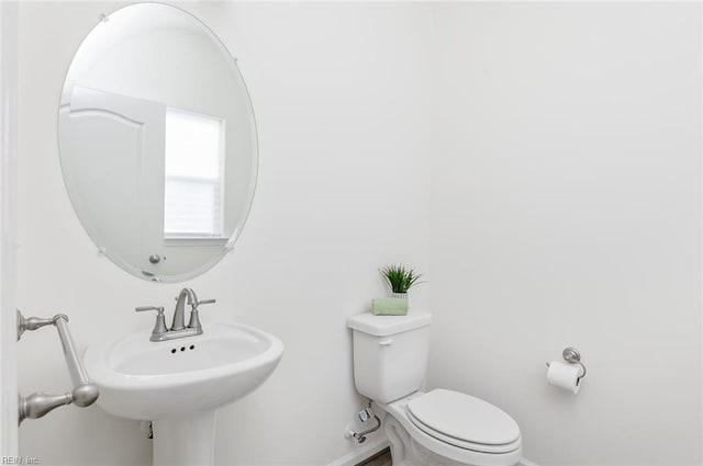 half bathroom featuring baseboards and toilet