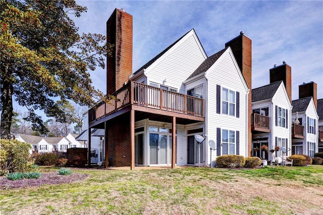 rear view of house featuring a chimney, a deck, and a yard