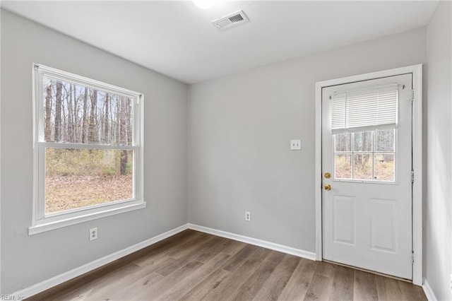 interior space with baseboards, visible vents, and wood finished floors