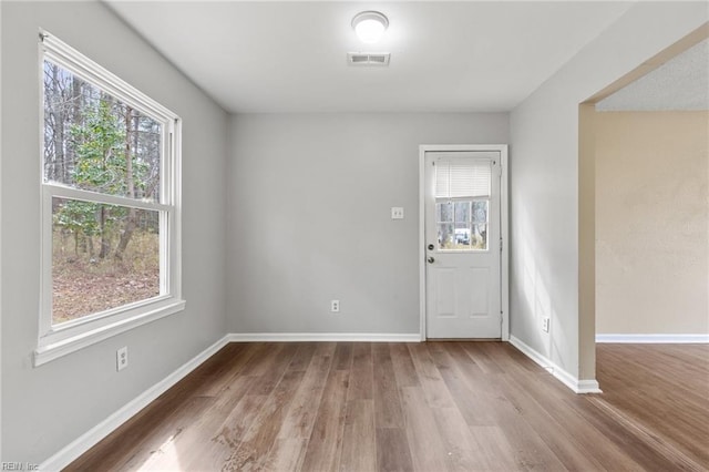 entryway with a wealth of natural light, visible vents, baseboards, and wood finished floors