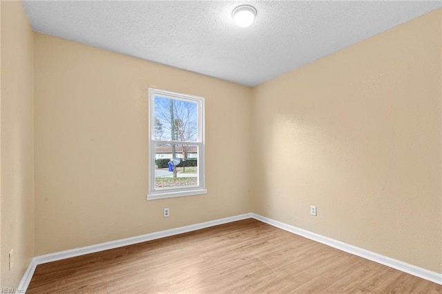 empty room with a textured ceiling, wood finished floors, and baseboards