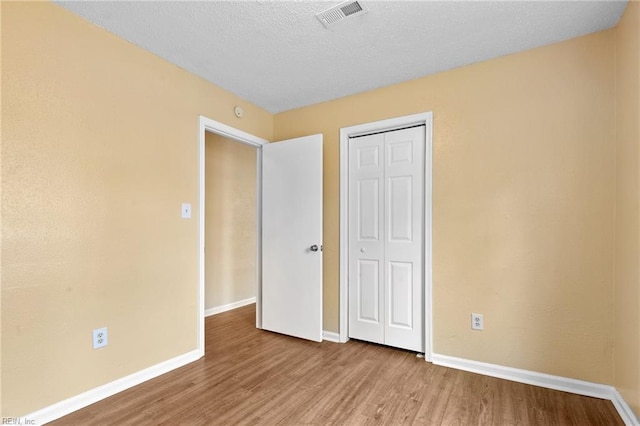 unfurnished bedroom featuring wood finished floors, visible vents, and baseboards