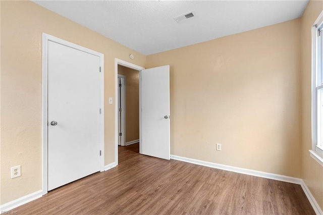 spare room with wood finished floors, visible vents, and baseboards