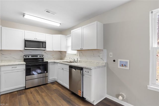 kitchen with appliances with stainless steel finishes, white cabinets, and a sink