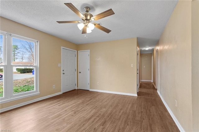 empty room featuring plenty of natural light, wood finished floors, and baseboards