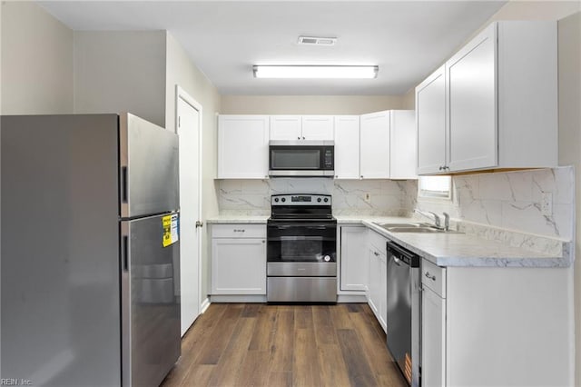 kitchen with decorative backsplash, dark wood-style floors, stainless steel appliances, light countertops, and a sink