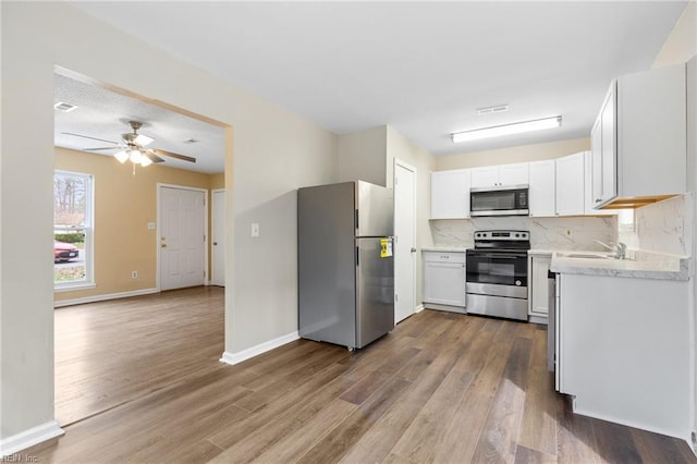 kitchen featuring a sink, stainless steel appliances, backsplash, and wood finished floors