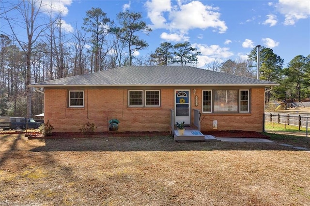 view of front of property with brick siding, a front lawn, and fence