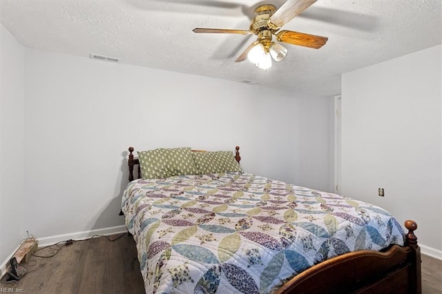 bedroom featuring a textured ceiling, dark wood-style flooring, a ceiling fan, visible vents, and baseboards