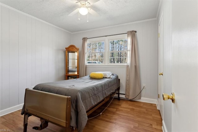 bedroom featuring a baseboard radiator, ornamental molding, ceiling fan, a textured ceiling, and wood finished floors