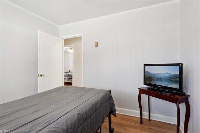 bedroom featuring ornamental molding, baseboards, and wood finished floors