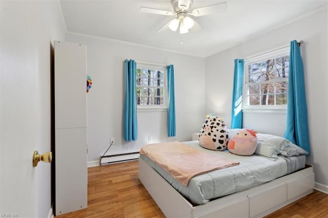 bedroom featuring light wood-style flooring, multiple windows, and a baseboard heating unit