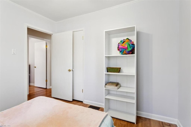 bedroom featuring light wood-style floors, visible vents, ornamental molding, and baseboards