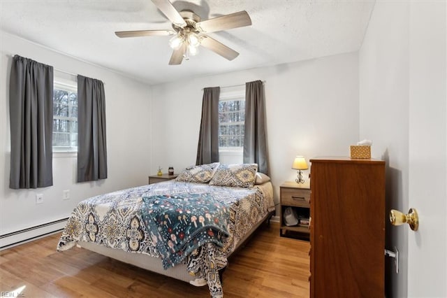 bedroom with a baseboard radiator, ceiling fan, and wood finished floors