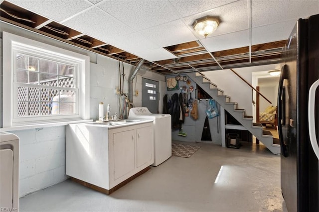 basement with a sink, washer and dryer, stairway, freestanding refrigerator, and concrete block wall