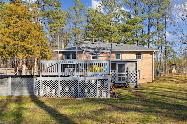 rear view of house with a sunroom, a deck, a lawn, and brick siding