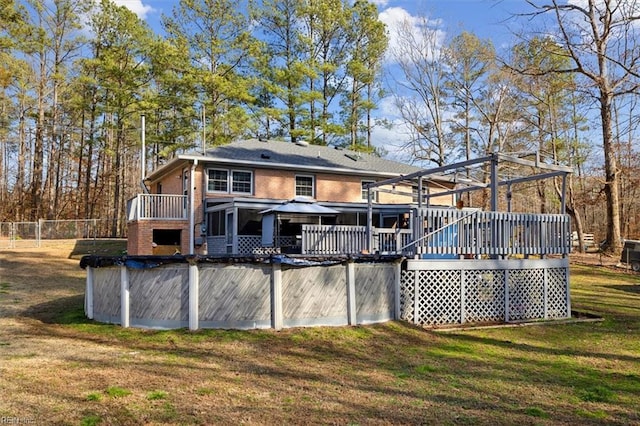 back of property featuring a yard, brick siding, a wooden deck, and fence