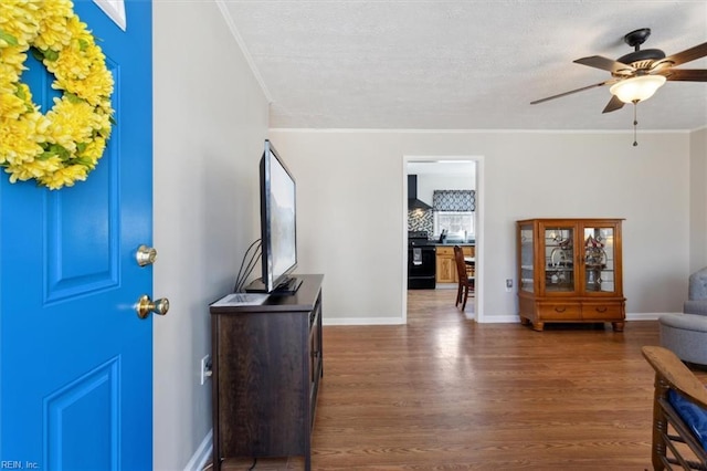 foyer with dark wood-type flooring, crown molding, baseboards, and ceiling fan